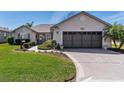 A charming home featuring a well-kept lawn, dark garage door, and manicured shrubs at 12199 Se 175Th Loop, Summerfield, FL 34491