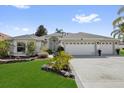 Beautiful home exterior with a well-manicured lawn, mature landscaping, and a spacious three-car garage at 1367 Honea Path, The Villages, FL 32162