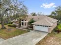 An aerial view of a peach-colored two-story home with a driveway and mature landscaping at 1602 Oak Hollow Rd, Clermont, FL 34711