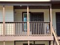 Condo balcony with brown railings, tan siding, and view of the front door at 18203 Sandalwood Dr # 18203, Wildwood, FL 34785