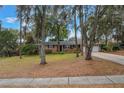 Beautiful one-story brick home with manicured front yard, mature trees, and a spacious driveway leading to a two-car garage at 1840 12Th St, Clermont, FL 34711