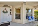 Inviting front porch with a white metal bench with blue cushions and a door with a decorative wreath at 1923 Greeleyville Ter, The Villages, FL 32162