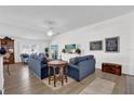 Bright living room with vaulted ceilings, wood floors, two blue couches, and sliding glass doors at 1923 Greeleyville Ter, The Villages, FL 32162