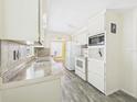 Bright kitchen features lots of cabinet space, laminate countertops, white appliances, and luxury vinyl plank flooring at 2 Heather Ln, Fruitland Park, FL 34731