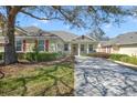 Inviting one-story home with a well-manicured lawn, mature trees, and a cozy front porch, enhancing curb appeal at 22027 Belgian Ct, Mount Dora, FL 32757