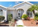 Inviting front entrance with arched doorway, adorned with decorative plants and a welcoming walkway at 25265 Lost Oak Cir, Leesburg, FL 34748