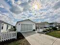 Desirable home featuring a white picket fence, an attached garage, and a sunny sky at 2910 Barboza Dr, The Villages, FL 32162