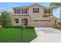 Inviting two-story home with a manicured lawn, decorative shutters, and an attached two-car garage at 30342 Gidran Ter, Mount Dora, FL 32757