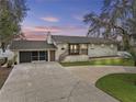 Charming single-story home with brick exterior, front porch, and a spacious driveway at dusk at 31400 Saunders Dr, Tavares, FL 32778