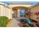 Charming front entrance with decorative door, arched window, complemented by colorful plants and a welcoming walkway at 3144 Mayflower Loop, The Villages, FL 32163