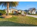 Beautiful single-story home with a lush green lawn, mature palm trees, and meticulous landscaping, creating curb appeal at 3144 Mayflower Loop, The Villages, FL 32163