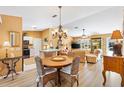 Open dining area with a wooden table, wicker chairs, and a chandelier, seamlessly connected to the kitchen and living room at 3349 Ashbrook Pl, The Villages, FL 32162