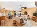 Inviting living room featuring hardwood floors, warm-toned walls, a ceiling fan, and a view to the kitchen and dining area at 3349 Ashbrook Pl, The Villages, FL 32162