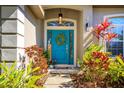 Inviting front entrance with a vibrant blue door, decorative wreath, colorful plants and a welcome sign at 519 Hearthglen Blvd, Winter Garden, FL 34787