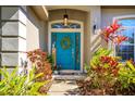 Inviting front entrance with a bright teal door, decorative wreath, transom window and colorful landscaping at 519 Hearthglen Blvd, Winter Garden, FL 34787