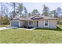 Attractive home with a neatly maintained lawn and a complementary color scheme, enhancing curb appeal at 565 Malauka Radl, Ocklawaha, FL 32179