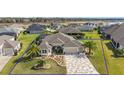 Beautiful single-story home with a manicured lawn, elegant landscaping, and a brick-paved driveway at 712 Krietemeyer Path, The Villages, FL 32163