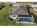 Aerial view of home featuring a screened-in pool, patio, and well-manicured landscaping at 712 Krietemeyer Path, The Villages, FL 32163