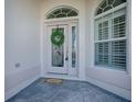 Close-up of the front door featuring decorative glass, sidelights, and a 'Welcome' mat at 7812 Se 167Th Mistwood Ln, The Villages, FL 32162