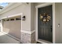 Close up on the front door with decorative wreath, stone accents and view of the garage at 10177 Spring Lake Dr, Clermont, FL 34711