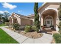 Inviting front entrance with a covered porch, arched doorway, and decorative landscaping for a warm welcome at 12626 Douglas Fir Ct, Clermont, FL 34711