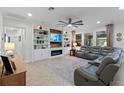 Bright living room features a large sectional sofa, custom built-ins, a fireplace, and a large ceiling fan at 16620 Caravaggio Loop, Montverde, FL 34756