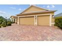 Spacious three-car garage with a brick paver driveway and well-maintained landscaping at 2050 Biller Cir, The Villages, FL 32163