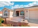 Inviting front entrance with a covered porch, decorative brick accents, and a two-car garage at 2311 Bramble Ter, The Villages, FL 32162