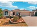 A one-story home featuring a neutral color palette, arched windows, and well-manicured landscaping at 2311 Bramble Ter, The Villages, FL 32162