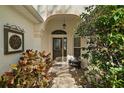 Inviting front entrance with an arched entryway, decorative sidelights, and lush landscaping creating a warm welcome at 2360 Unity Ter, The Villages, FL 32162