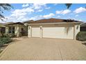 A well-maintained three-car garage with a paved driveway and mature landscaping around the property at 2360 Unity Ter, The Villages, FL 32162