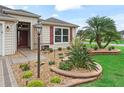 Landscaped front yard featuring stone accents, lush green grass, and a vibrant palm tree at 3047 Bevill Ln, The Villages, FL 32163