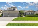 Well-manicured lawn, three-car garage, and pristine home exterior under a blue sky at 4256 Fawn Meadows Cir, Clermont, FL 34711