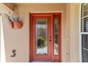 Close up of charming glass paneled front door with hanging planters and bronze colored hardware at 483 Cammarano Pl, The Villages, FL 32162