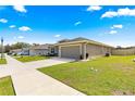 Home featuring a well-kept lawn, gray exterior, and an attached two-car garage at 10420 E 161St St, Summerfield, FL 34491