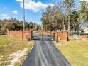 Long paved driveway leads to a gated brick entrance of the estate at 10944 Autumn Ln, Clermont, FL 34711