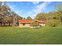 Charming single-story home featuring a vibrant red roof and a well-manicured lawn at 11740 E Highway 25, Ocklawaha, FL 32179