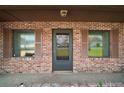 Close up of a brick front porch with a front door and windows with dark shutters at 12320 Blue Heron Way, Leesburg, FL 34788