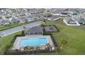 Community aerial view showcasing a sparkling pool, playground, and neatly arranged residential homes at 125 Sunny Day Way, Davenport, FL 33897