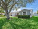 View of the lush front lawn and gray siding of the home, complemented by green shrubbery at 17442 Se 79Th Lovewood Ave, The Villages, FL 32162