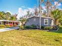 Single Gathering home featuring lawn, tropical landscaping, and hardscaped flower bed at 3221 Myakka River Rd, Tavares, FL 32778