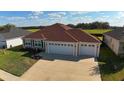 Attractive house with a wide driveway and three-car garage, set against a backdrop of green fields at 3290 Sennett Cir, Oxford, FL 34484