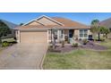 Single-story home featuring a beautifully landscaped yard, beige exterior, and a charming blue front door at 3330 Mayflower Loop, The Villages, FL 32163