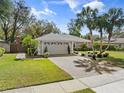Landscaped home showcasing a brick driveway, green lawn, and mature palm trees at 3400 Foxboro Ct, Mount Dora, FL 32757