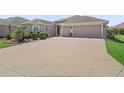 Spacious driveway leading to a two-car garage, surrounded by lush landscaping and a well-maintained lawn at 3540 O'Brien Pl, The Villages, FL 32163