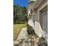 A side view of the home featuring a small sidewalk and green bushes at 390 Colonade Ct, Kissimmee, FL 34758