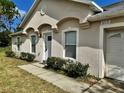 Close up of the front entrance and its stucco facade and manicured bushes at 390 Colonade Ct, Kissimmee, FL 34758