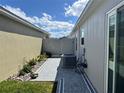 A narrow side yard featuring decorative stone, plants, and an AC unit with a privacy fence in the background at 511 Van Deen Pl, The Villages, FL 34762