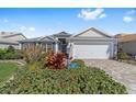 Charming single-story home with well-manicured landscaping, brick driveway, and attached two-car garage at 565 Brighton Dr, The Villages, FL 32162