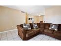 Cozy living room showcasing tiled floors, a large brown couch with accent pillows, and neutral paint at 7036 Clarcona Ocoee Dr, Orlando, FL 32818